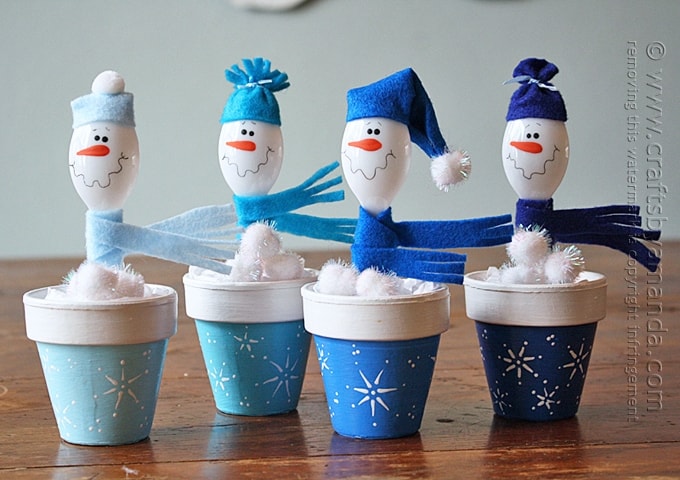 Cuatro macetas de barro con cucharas de plástico como muñecos de nieve