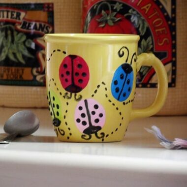 yellow coffee mug with painted ladybugs on it