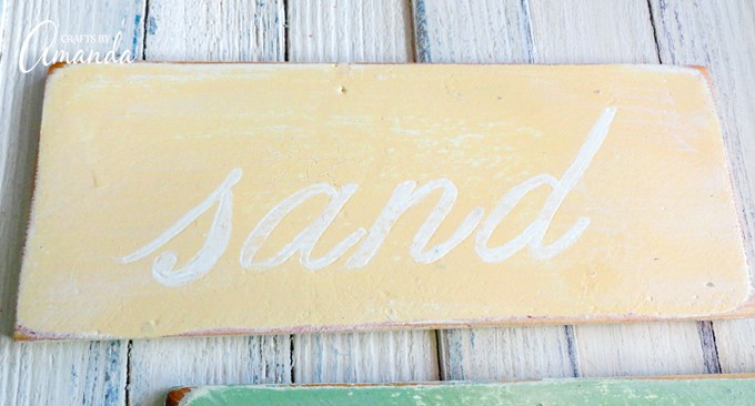Weathered beach sign SAND yellow