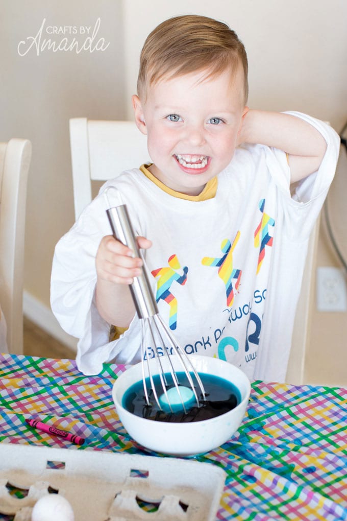 young boy dyeing easter eggs with a whisk