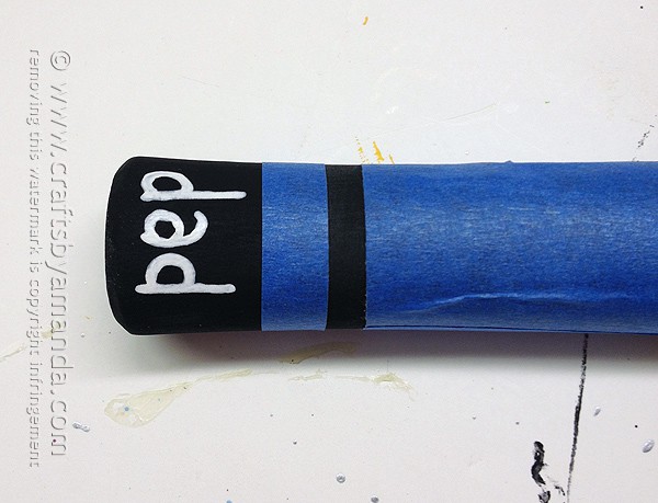 Add painter's tape to the hammer's handle to create stripes and write dad on the bottom
