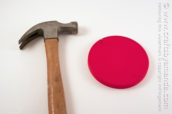 hammer next to a red plastic lid