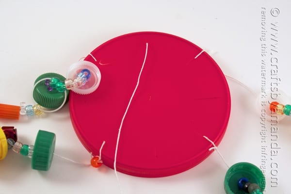 string threaded through holes in a plastic lid