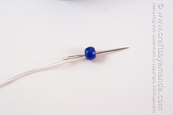 bead threading through needle with a string