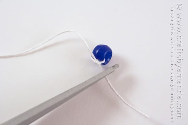 Thread the needle through one bead. Tie a few knots around that bead at the end of the string. 
