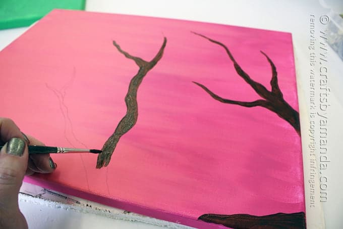 painting a tree branch on pink canvas