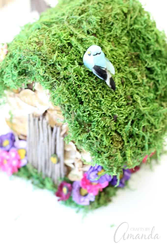 faux blue bird on top of birdhouse