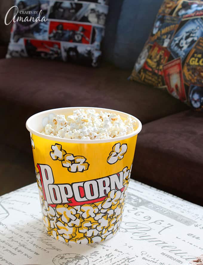 Decorate your family room with movie theater themed decor for a fun mini theater room experience! Fun movie room wall art, zombie pillows, a real popcorn maker and even candy and snacks make this room a fun place for family movie night.