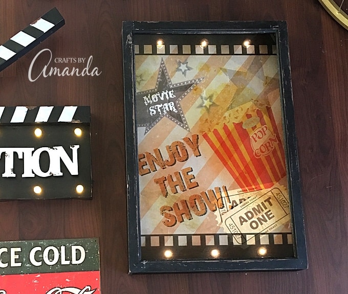 Decorate your family room with movie theater themed decor for a fun mini theater room experience! Fun movie room wall art, zombie pillows, a real popcorn maker and even candy and snacks make this room a fun place for family movie night.