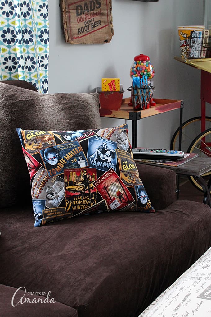 Decorate your family room with movie theater themed decor for a fun mini theater room experience! Fun movie room wall art, zombie pillows, a real popcorn maker and even candy and snacks make this room a fun place for family movie night.