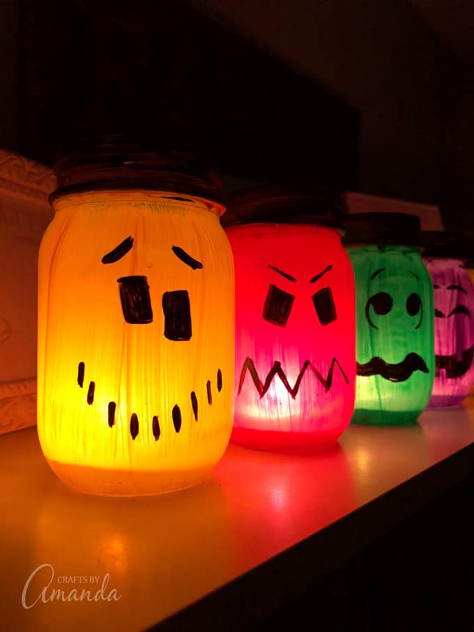 painted halloween luminaries on a shelf with candle lights