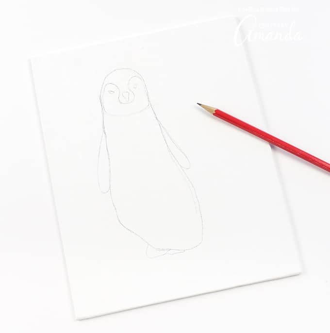 After gathering supplies, trace your child's shoe or sock-covered foot on the canvas panel. Within the shoe, sketch a drawing of a penguin chick. I added flat wings, a beak, eyes, and the outline of the penguin chick's feathers.
