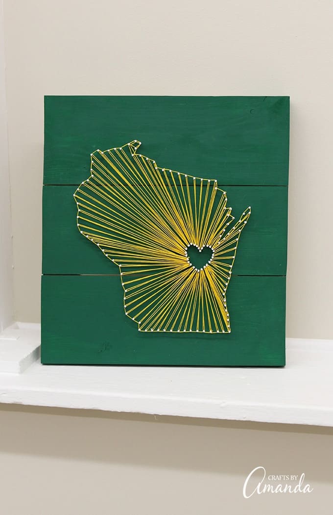 State string art makes a great gift and it's a fun craft project for adults. This one has a green and gold color scheme because the gift recipient is a Green Bay Packer fan, however stained wood and white string is a popular choice with these types of projects.