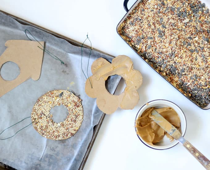 spreading peanut butter on cardboard for birdseed
