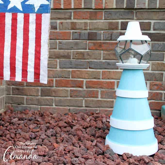 nautical themed clay pot lighthouse sitting in a bed of rocks