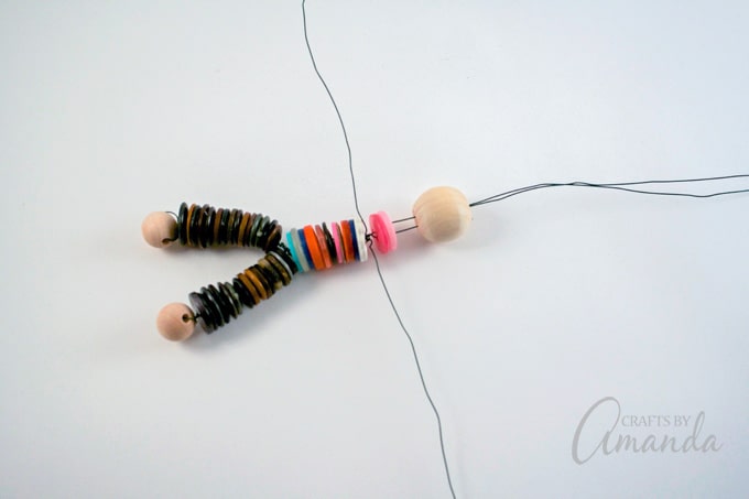 Add two buttons to the wire pointed up then add the large round bead.