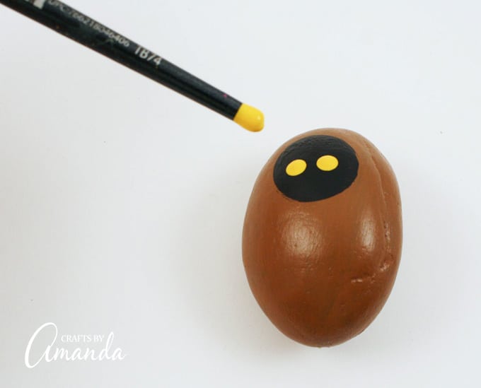 Using the handle end of your paintbrush dipped in dark yellow paint, add two eyes to the black paint.