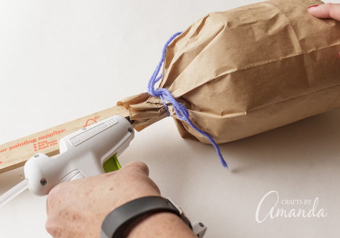 Secure the ends of the bag to the paint stir stick using hot glue.