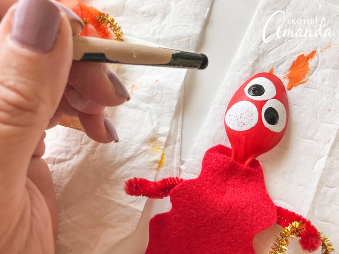 Drawing on eyeballs to red plastic spoon monster