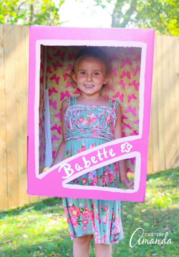 girl standing inside a pink doll box costume