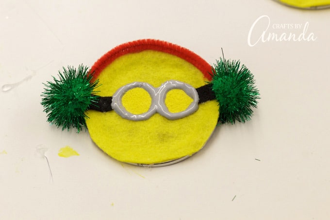 For the caroling minion, cut pipe cleaner to fit around the top of the minion's head then glue a pom poms to the sides.
