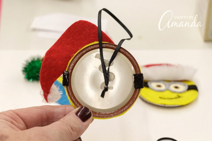 Tie ribbon into a loop hanger and glue to the back of the canning lid then cover with another yellow felt circle.
