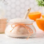 orange bath salts in a jar with a spoon