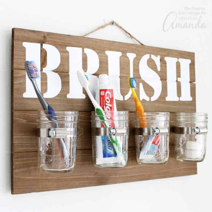 Mason Jar Bathroom Organizer hanging on wall with toothbrushes and toothpaste