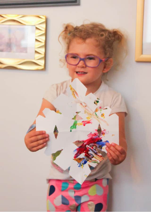 toddler holding paper snowflake