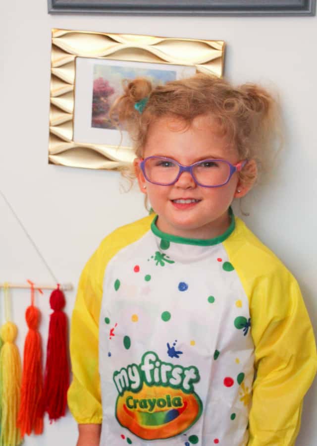 toddler smiling wearing smock