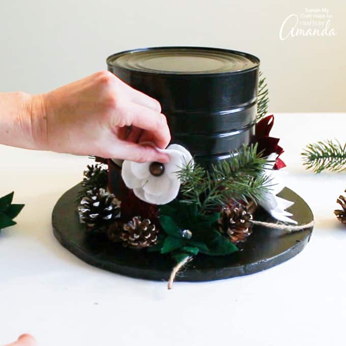 Adding felt flowers and greenery to snowman hat centerpiece