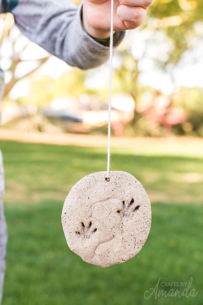 child holding a coffee ground fossil ornament on a string