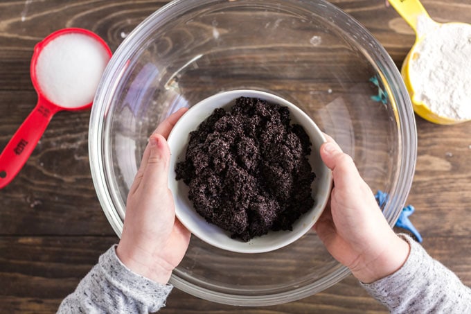 child holding bowl of coffee ground