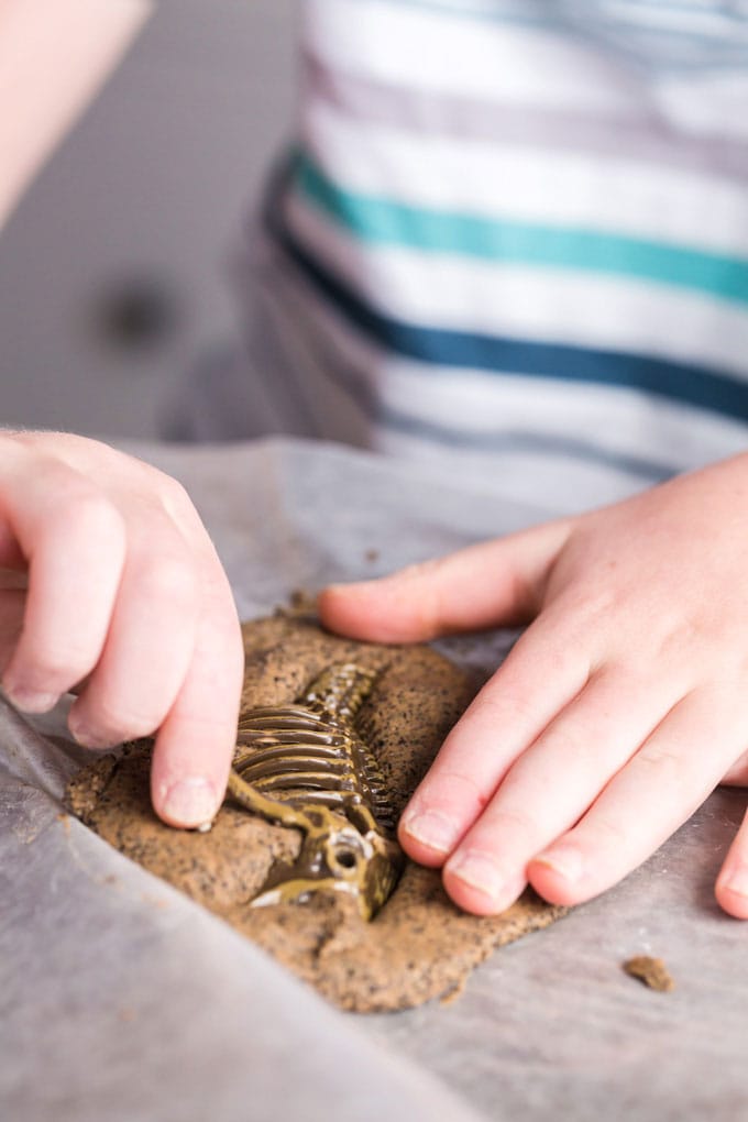 child pressing object into coffee ground salt dough