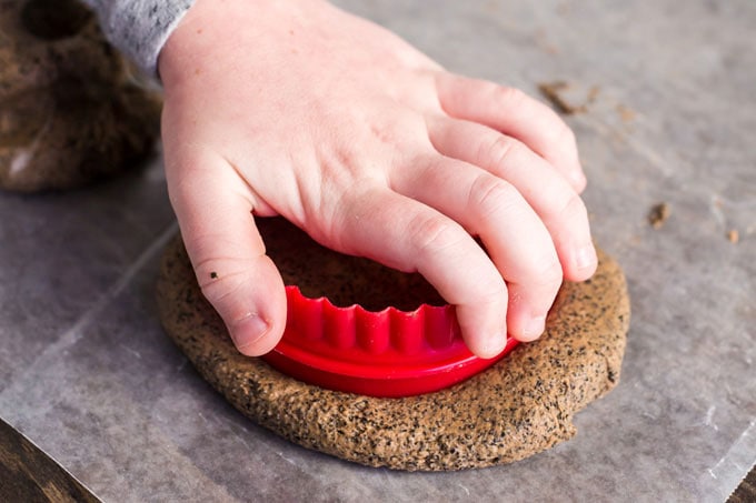 child pressing round cookie cutter into salt dough