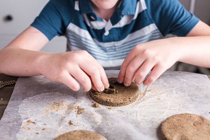 child pressing object into coffee ground salt dough