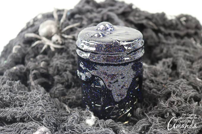 black glitter slime overflowing in mason jar