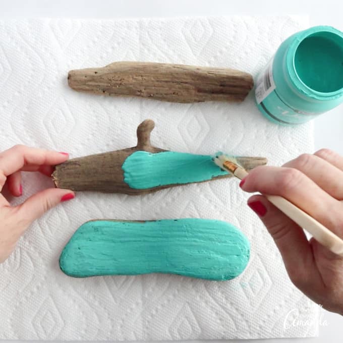painting driftwood pieces with turquoise paint