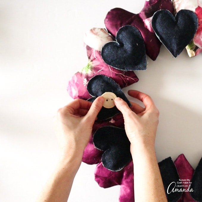 attaching wooden button to heart fabric wreath