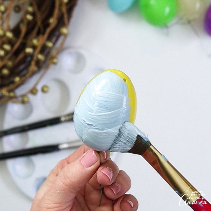 pintando ovos de páscoa de plástico em tons pastel