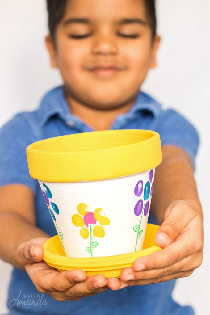little boy holding a painted flower pot