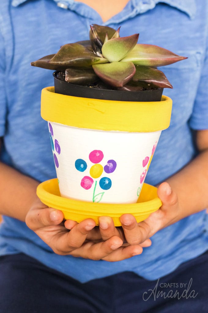 little boy holding a fingerprint flower pot
