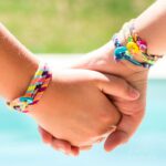 two girls holding hands wearing embroidery floss bracelets