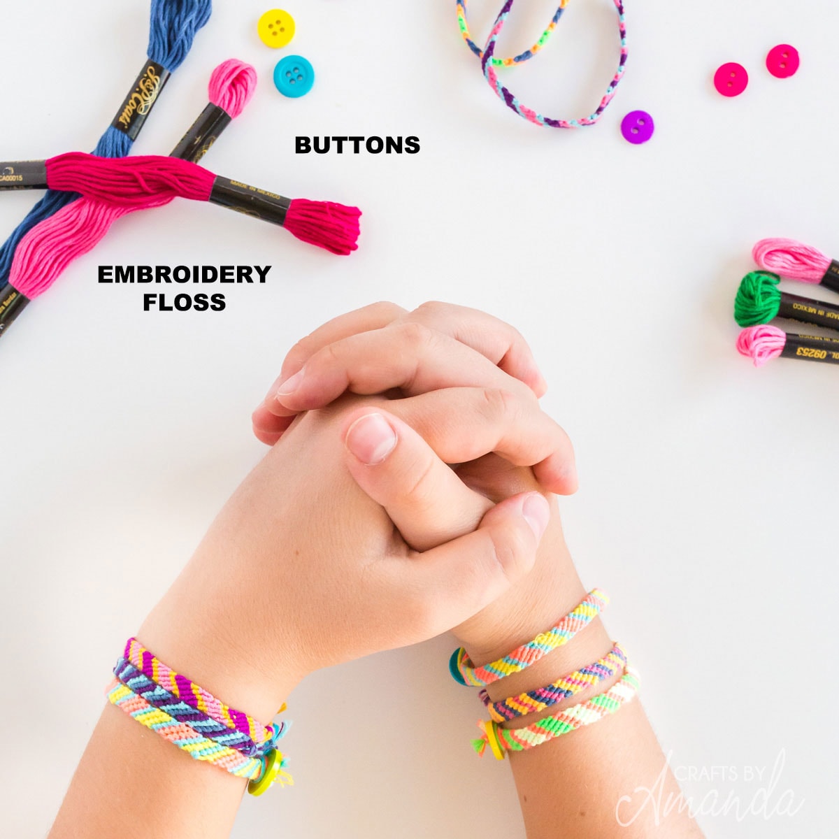 supplies for friendship bracelets and a girl's hands clasped together
