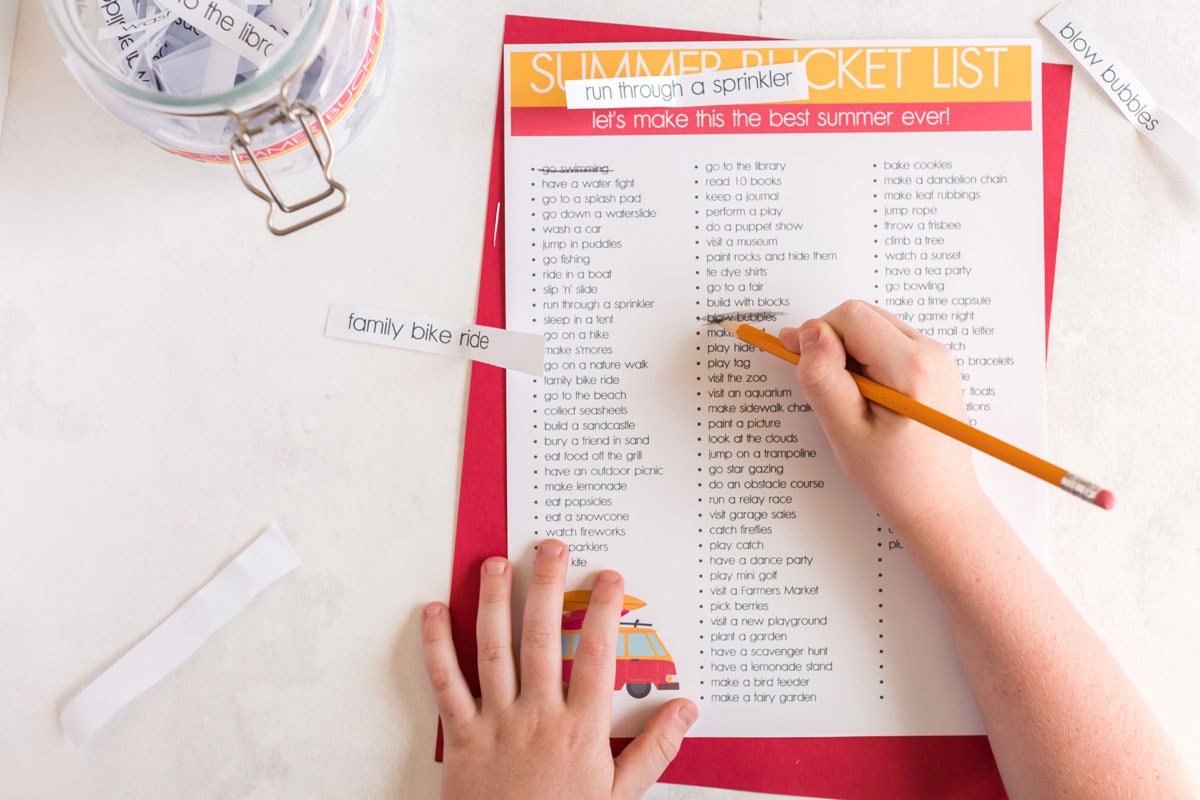 niño tachando un elemento de una lista con un lápiz | Lista de deseos