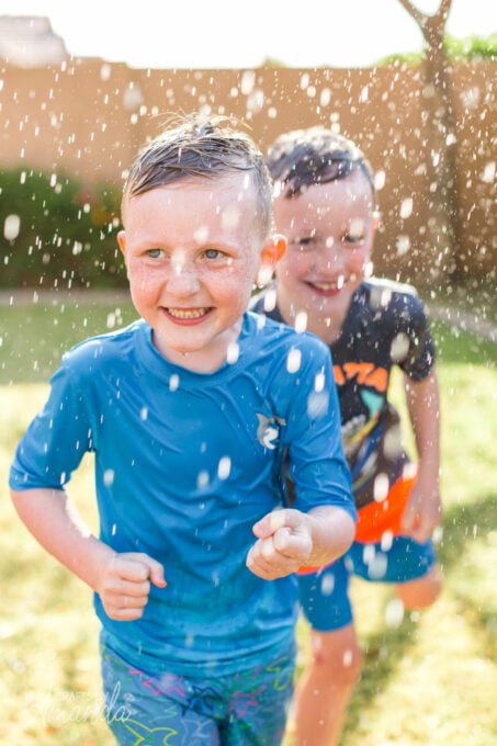 little boys running through sprinkler