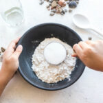 child adding flour and salt to a bowl