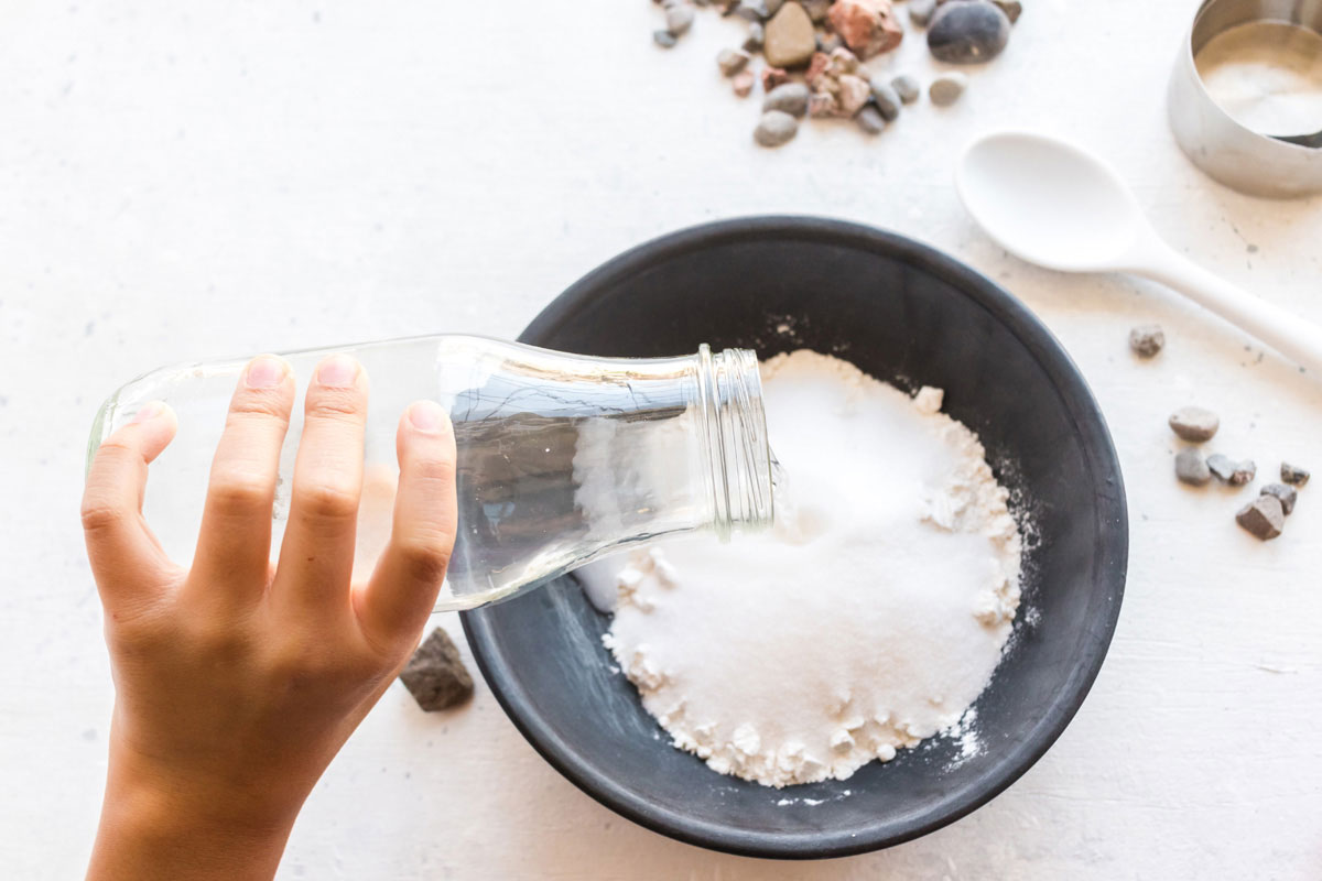ребенок добавляет воду в соль и муку в миску