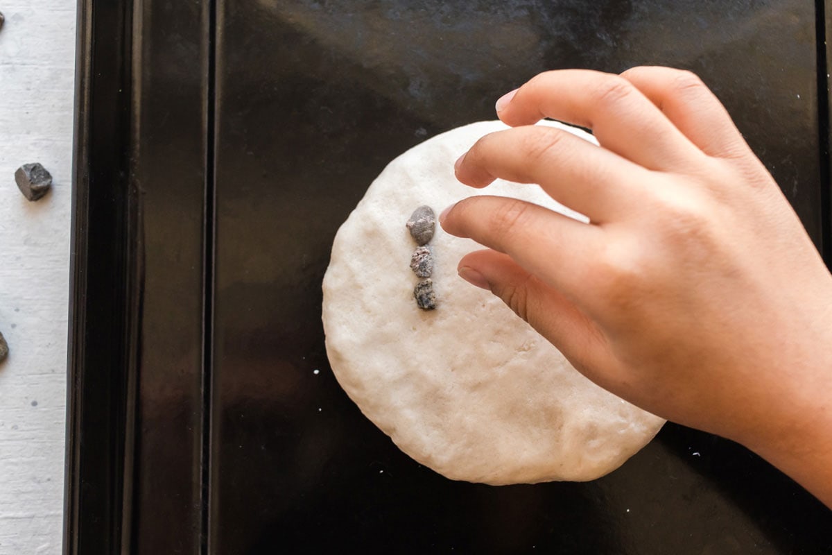 Child placing rocks into a bowl of salt dough