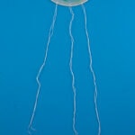 three strings hanging from plastic lid suncatcher